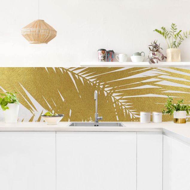 crédence cuisine en verre Vue à travers des feuilles de palmier dorées